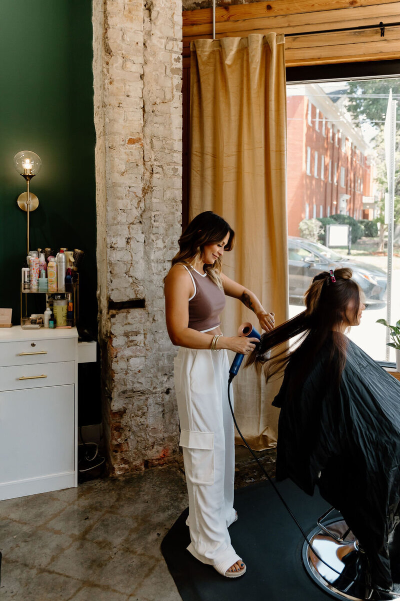 Hairstylist performing a Brazilian blowout treatment at The Vanity Hair Studio in Griffin, GA, delivering smooth, frizz-free, and shiny hair with long-lasting results.