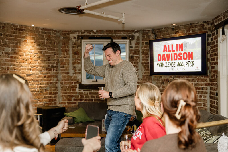 Man celebrating a win during a corporate event with guest in the background