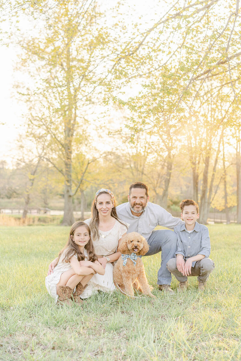 family of 4 huddled with their dog during spring mini session in Prince William County, Virginia