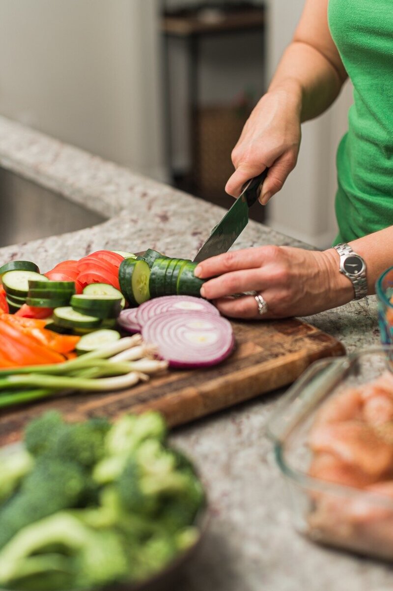 Woman slicing vegetables in kitchen as part of clean eating plan for weight loss