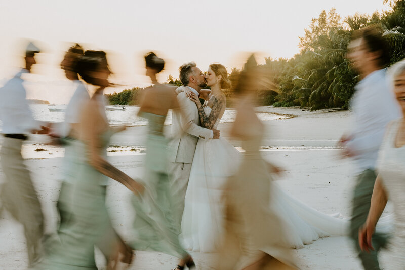 La mariée entourée de ses demoiselles d'honneur aux robes couleur pêche et corail, riants et complices lors d'une séance photo mariage.