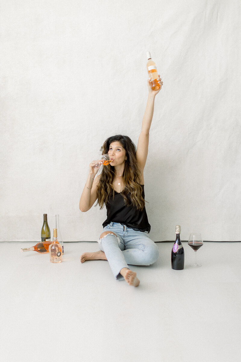 A fun professional headshot/branding session in a Dallas photography studio of local business owner drinking wine.