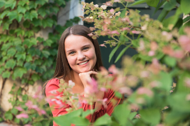 Senior girl smiling at the camera with beautiful flowers in the foreground