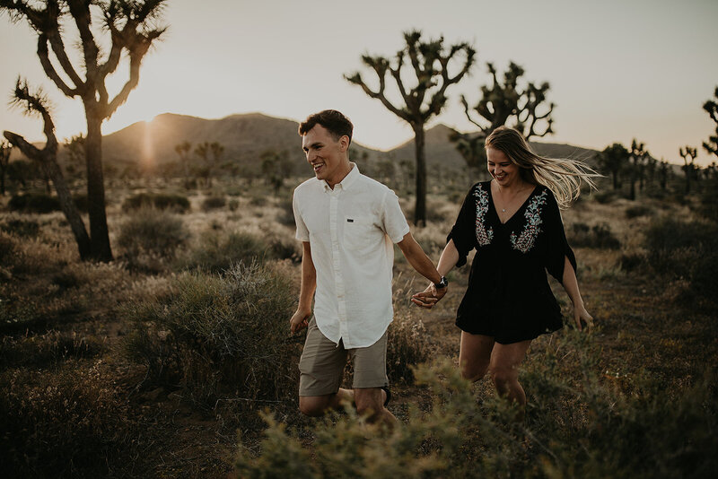 couple holding hands and walking through the desert