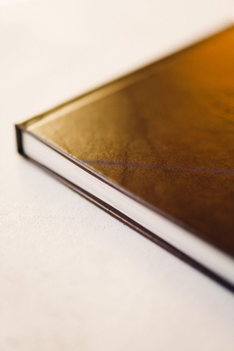 A brown leather wedding album with flat lay photos of the bride and groom's wedding day.