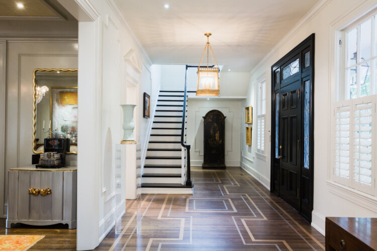 Image of grand staircase, unique hardwood floors, black door, casing, and more