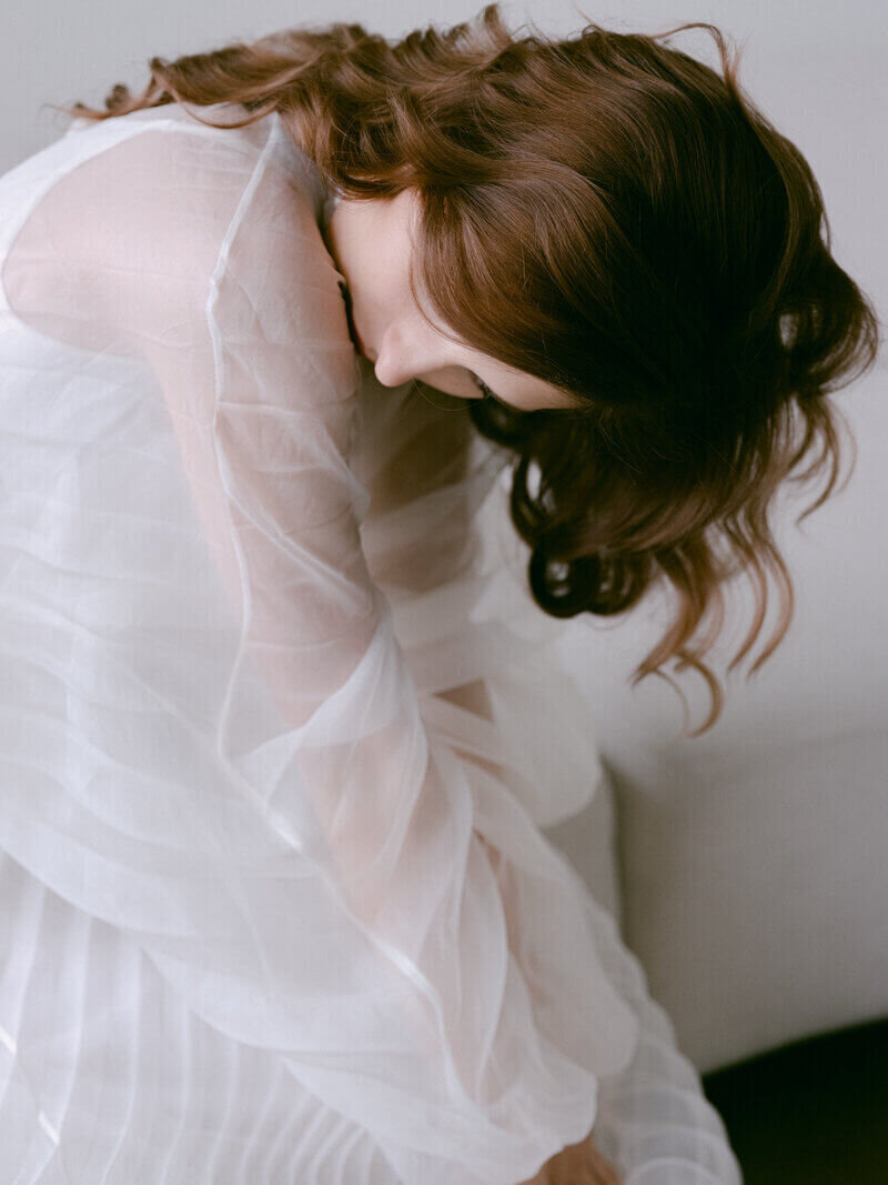 Fashion photo shoot model bening over wearing white dress