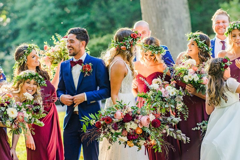 Wedding party bouquet with rich jewel tones in burgundy, coral and deep pink featuring Alaskan peonies, garden roses and local foliage