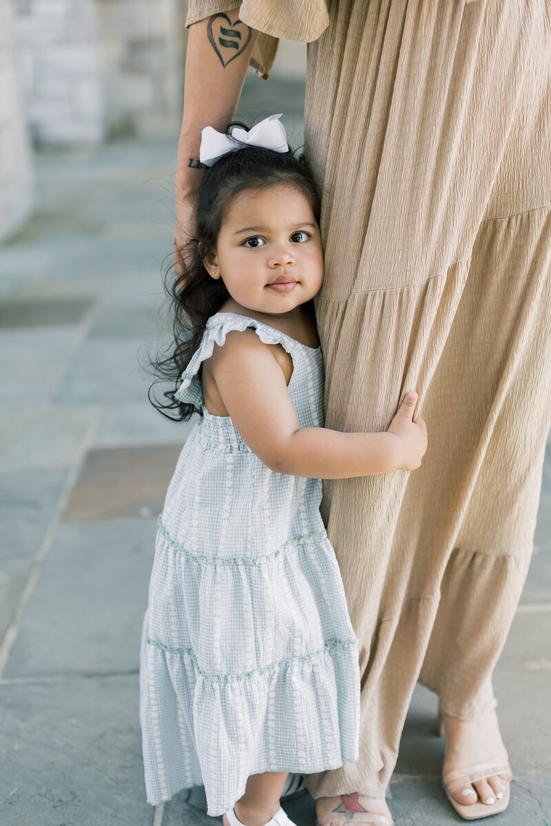 A little girl holds her mom during a mother daughter portrait session