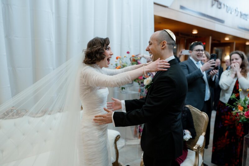 The bride and groom having a genuine first look during the Tisch portion of a Jewish wedding ceremony at Congregation Har Shalom in Potomac, Maryland