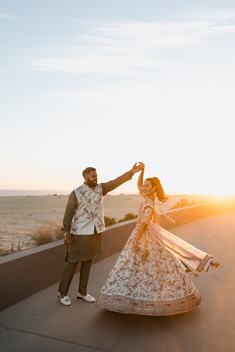 couple on beach boardwalk in front of sunset