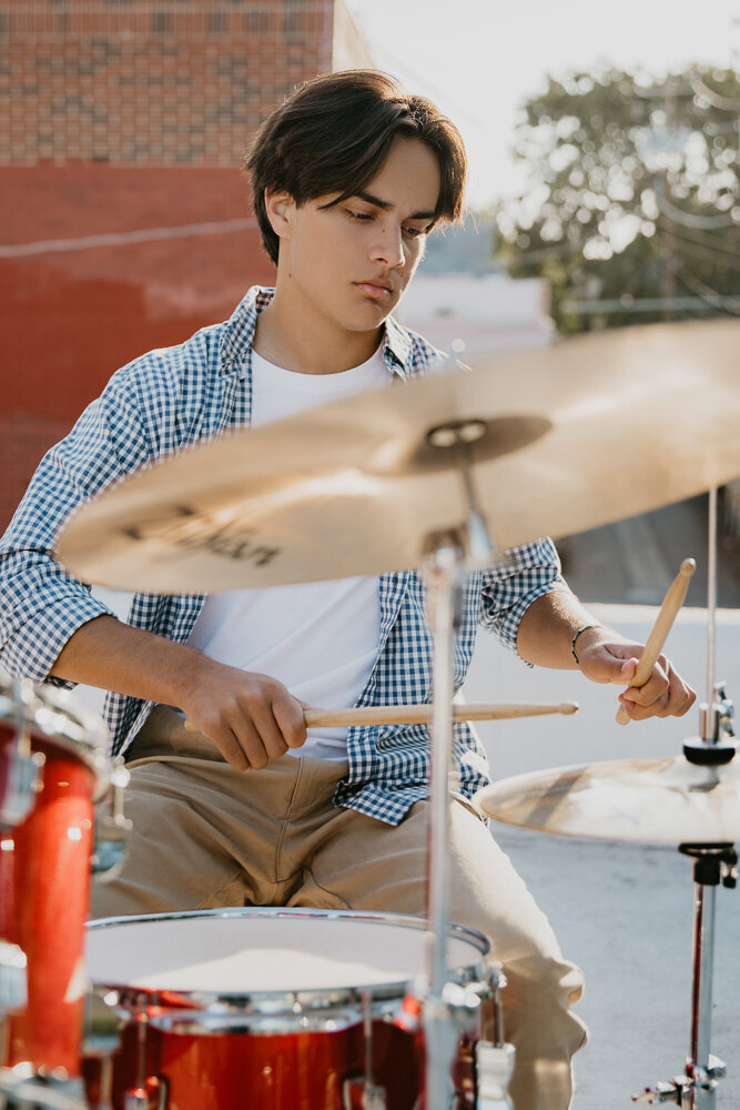 boy in checkered shirt playing drums on rooftop