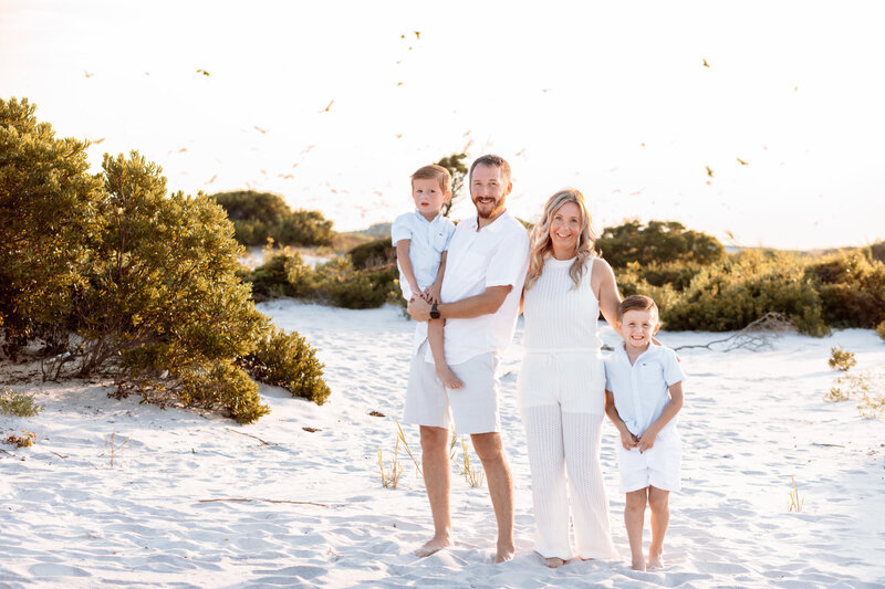 Family posing in the sand dunes at the beach during golden hour