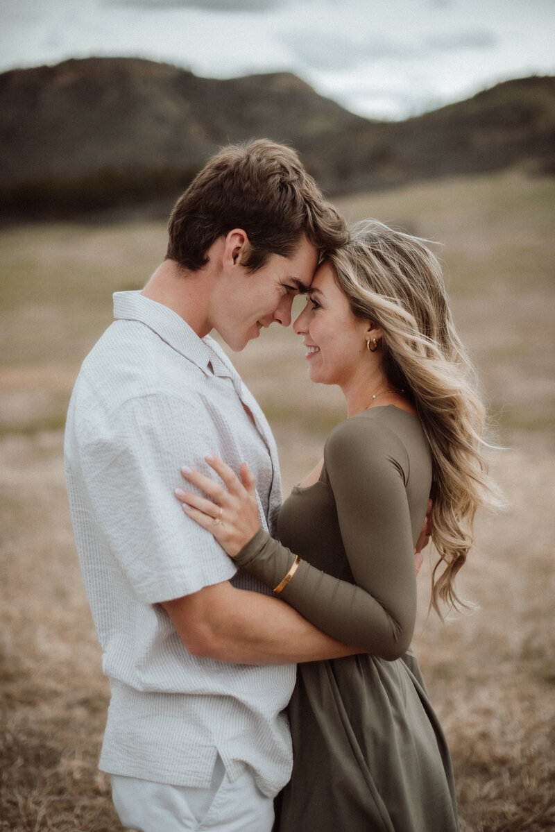 A young couple standing and holding each other in the golden hour glow at Dawson Butte Open Space Colorado. 