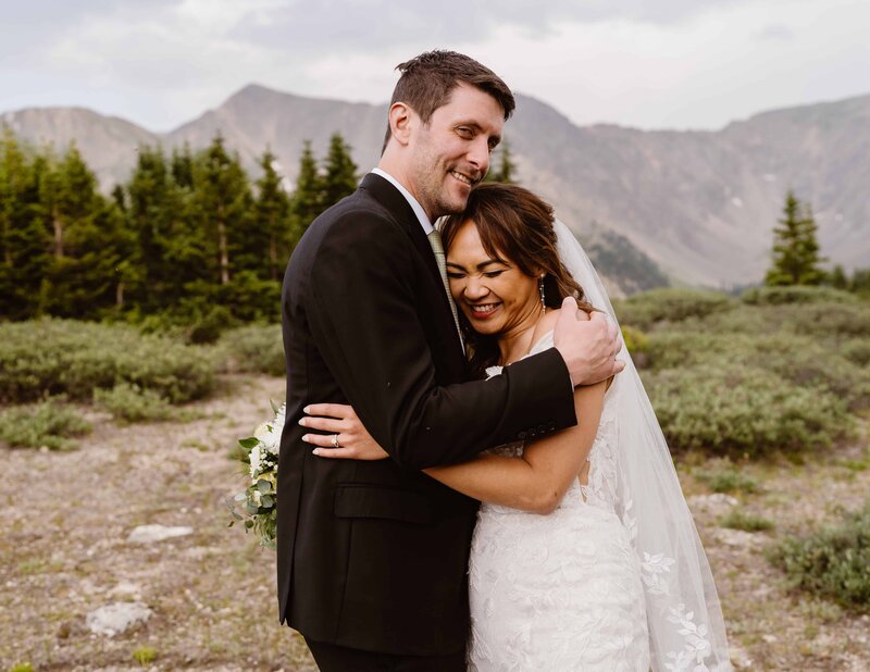 Couple laughs as they are snuggling together during their elopement at Loveland Pass, Colorado