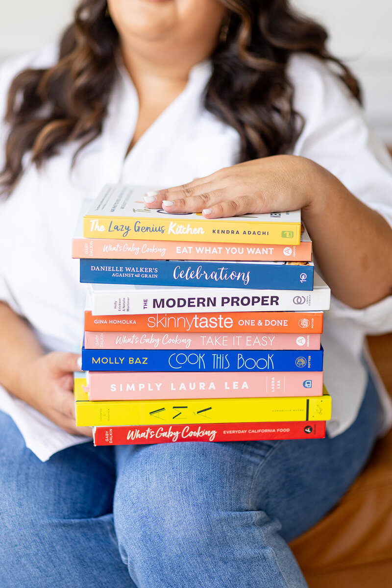 A stack of colorful books in Marissa Martinez's lap