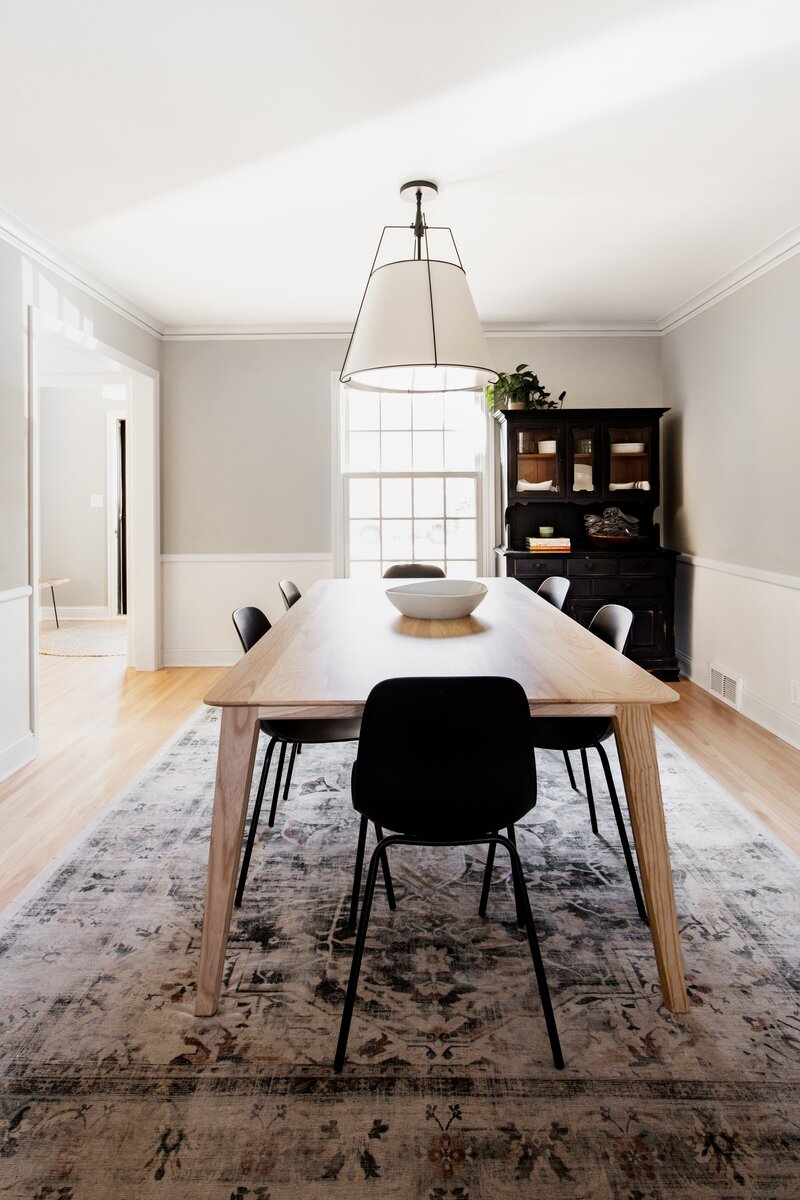Dining Room Remodel in Twin Cities Minnesota with Rug Wooden Table Lighting Black Chairs and Wood Floors