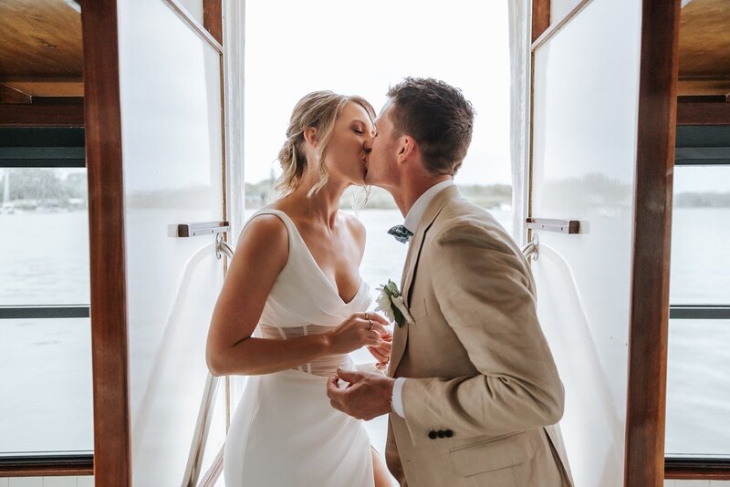 A bride and groom kissing at Noosa Boathouse