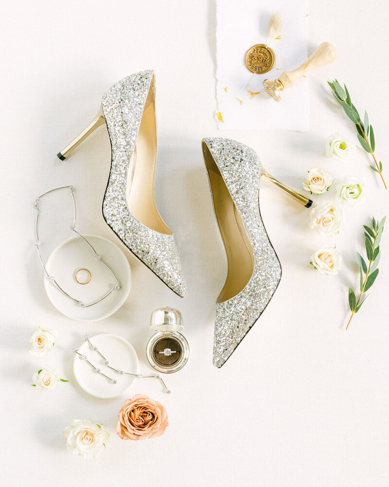 This beautifully styled layflat photograph showcases the bride’s wedding day details, featuring high-fashion shoes, a stunning ring, and other elegant accessories. The meticulous arrangement highlights the luxurious and refined elements of her special day.