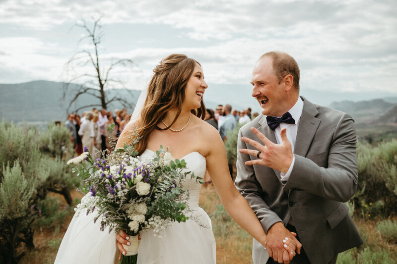 a couple dressed in white kissing on top of the mountain overlooking Osoyoos aftre their wedding