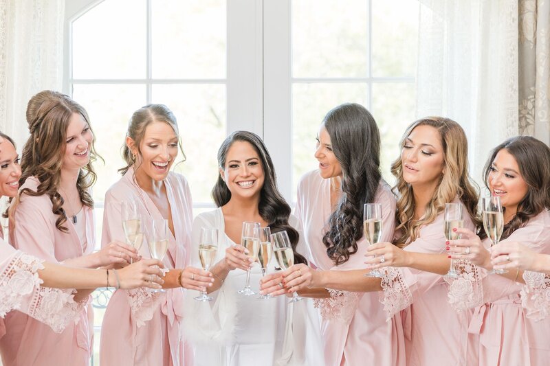 Bridesmaids and bride in robes toasting with champagne