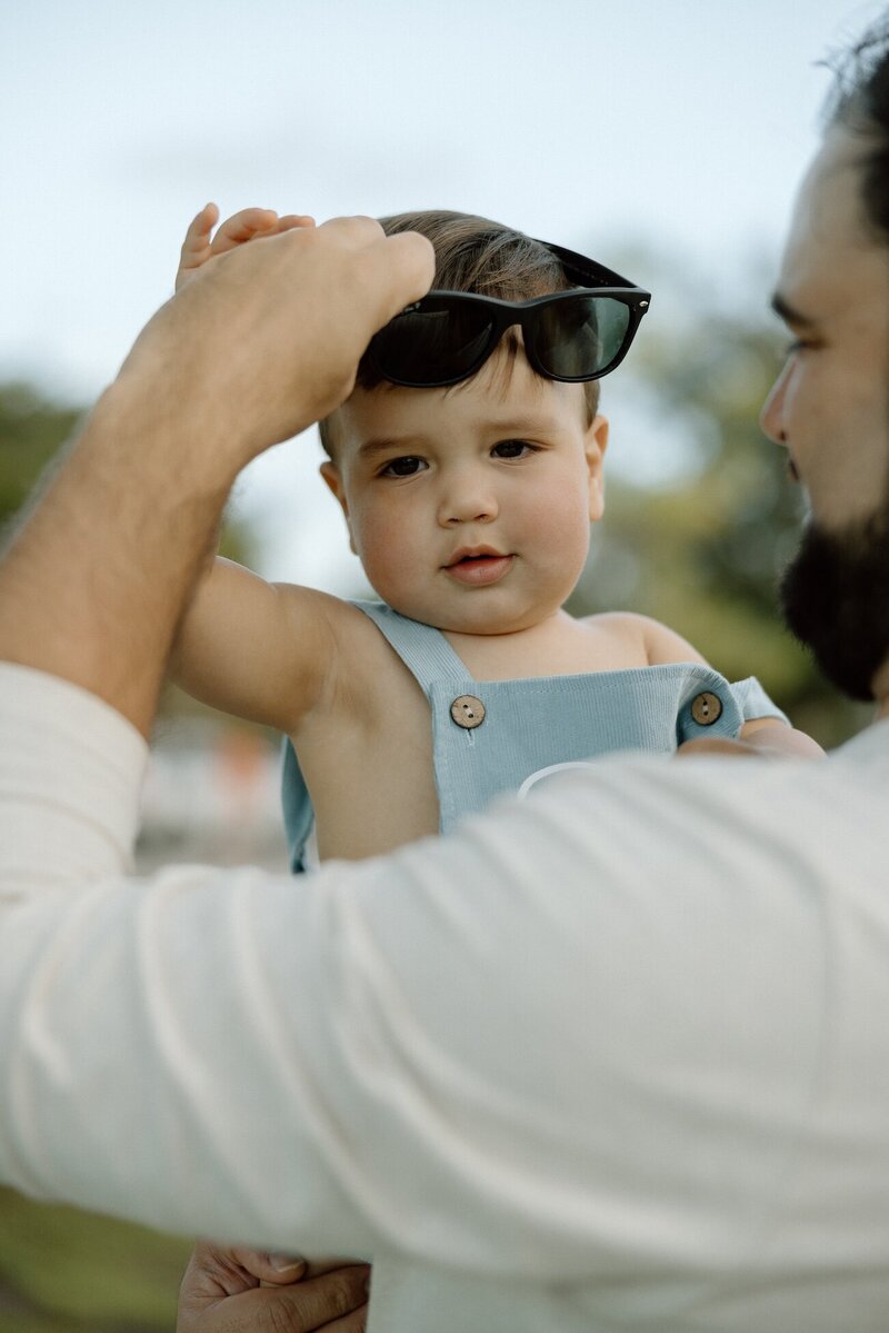 little boy wears dads sunglasses