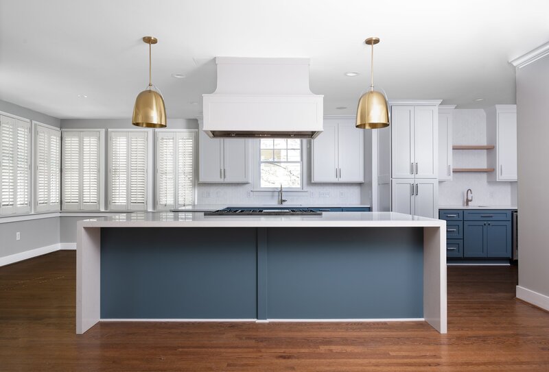 Spacious kitchen and dining area with black countertops, white cabinets, stainless steel appliances, and large windows