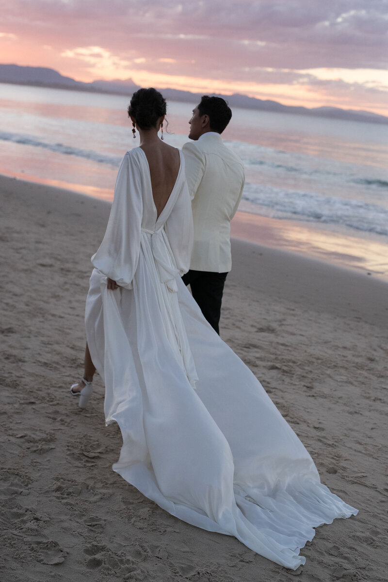 Couple at beach wedding, bride wearing long georgette silk wedding dress in wrap style