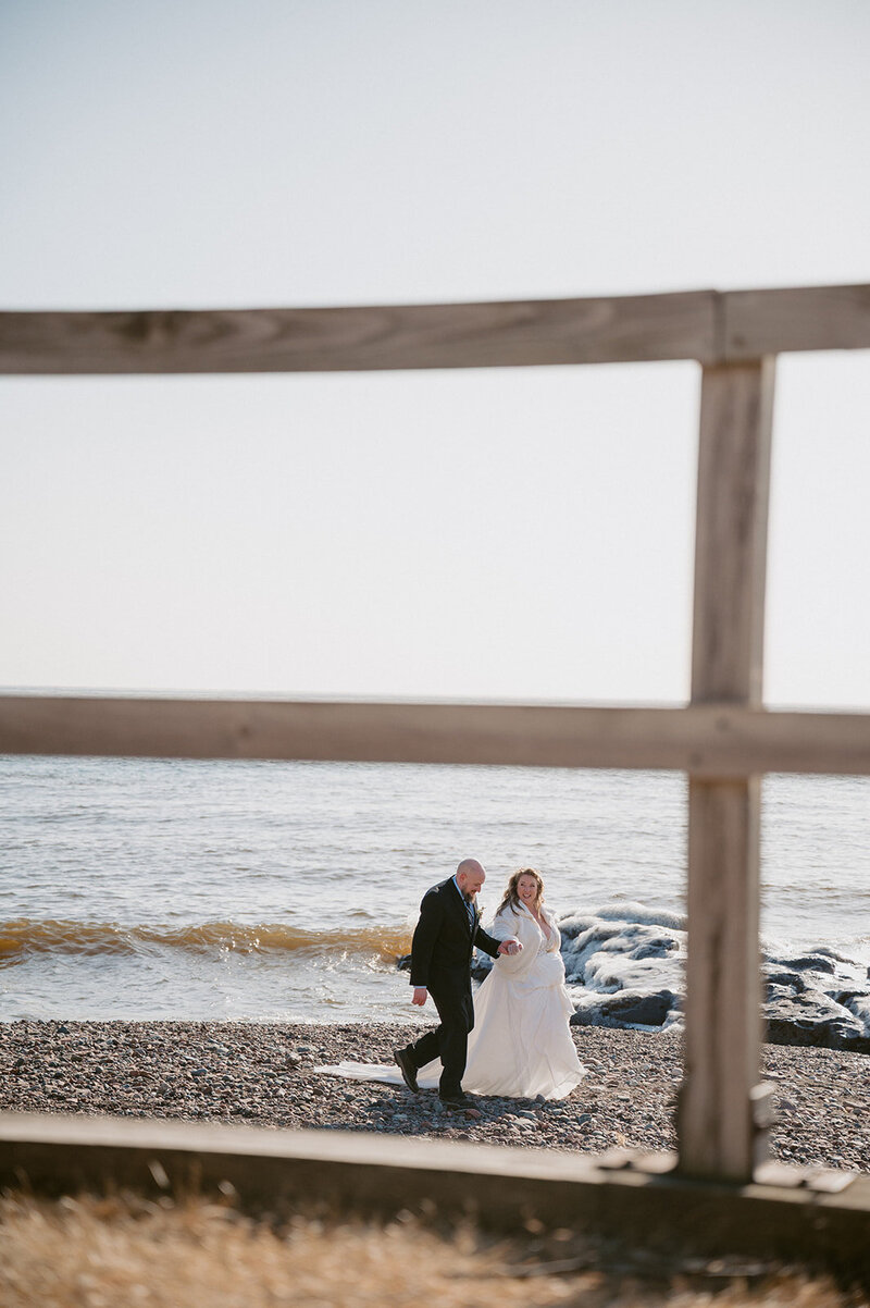 elopement couple hold hands and strolling on beach