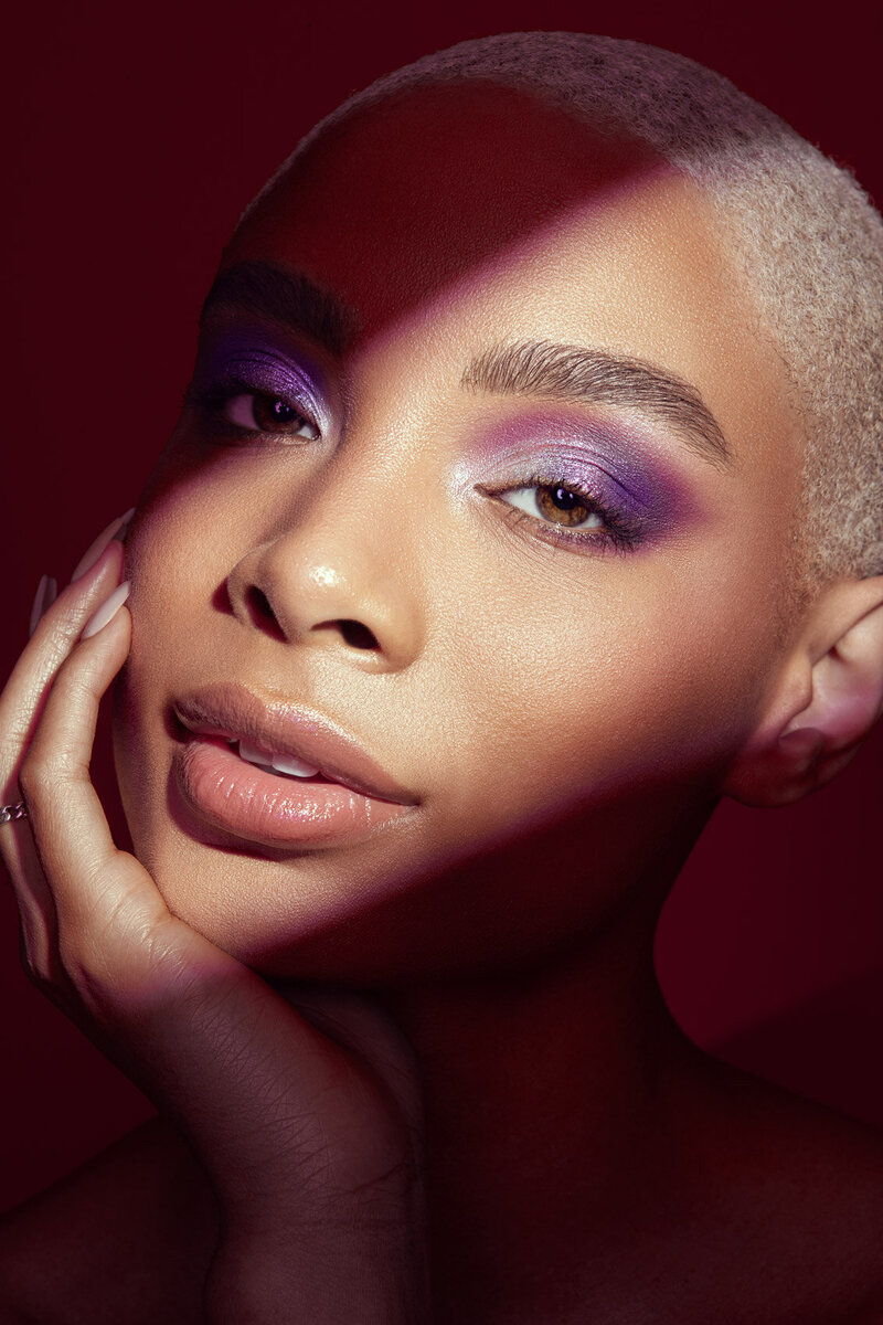 Close-up beauty shot of Raven with striking purple eyeshadow and glowing skin, captured by Ylva Erevall.