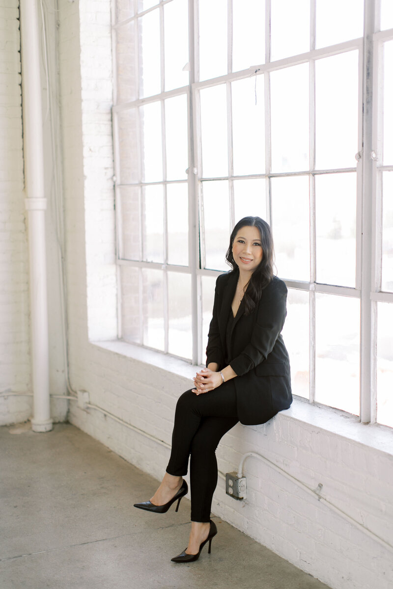 Image of professional in black suit sitting by window