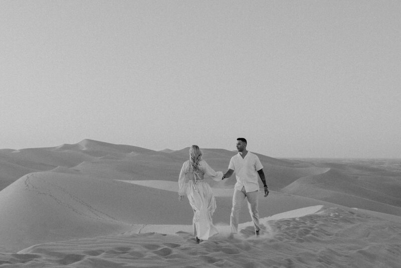Couple walking in the sand during their engagement photos at the Imperial Sand Dunes.