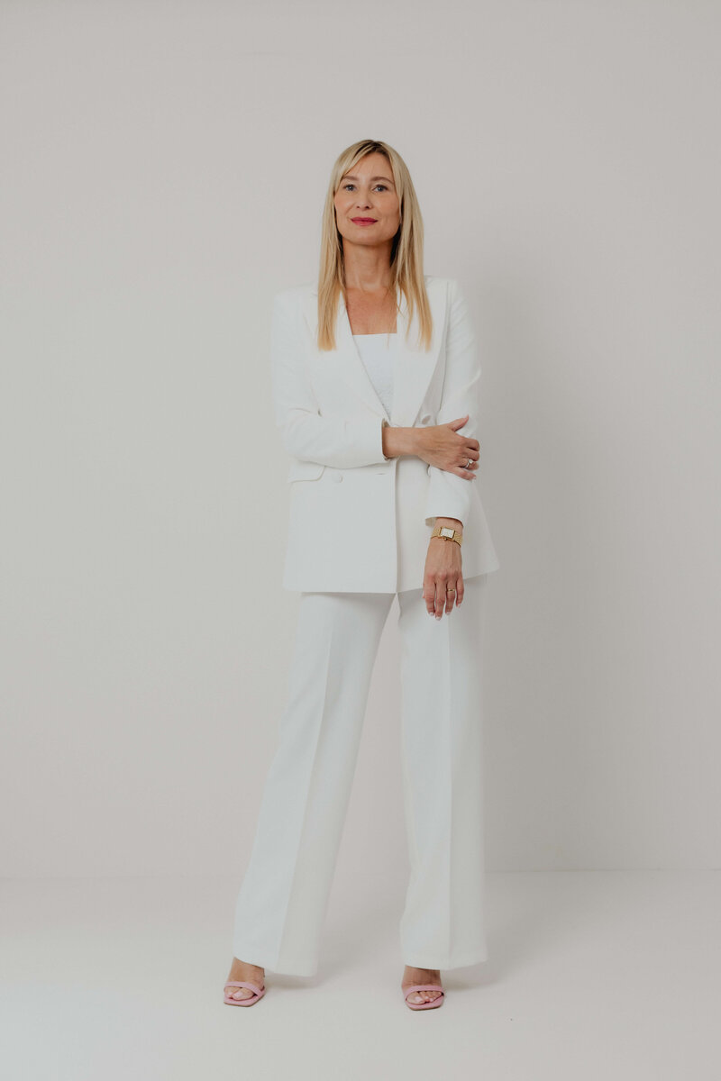 a women in a white power suite holding her arm.