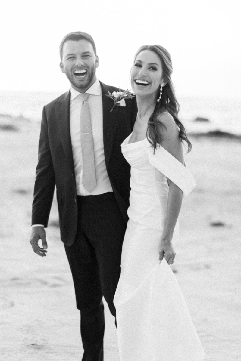 black and white photo of couple laughing during sunset portraits at pebble beach