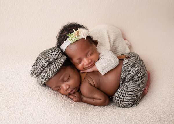 newborn twins sleeping in stacked pose on cream backdrop, gentle studio portrait — Birmingham Alabama