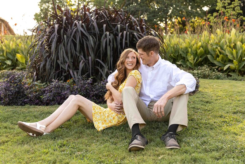 man and woman sitting on the grass while woman leans against the man