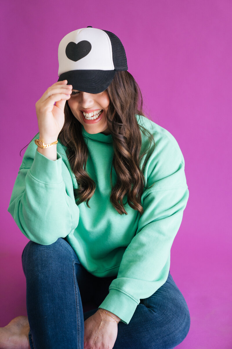 heather holding onto brim of black hat
