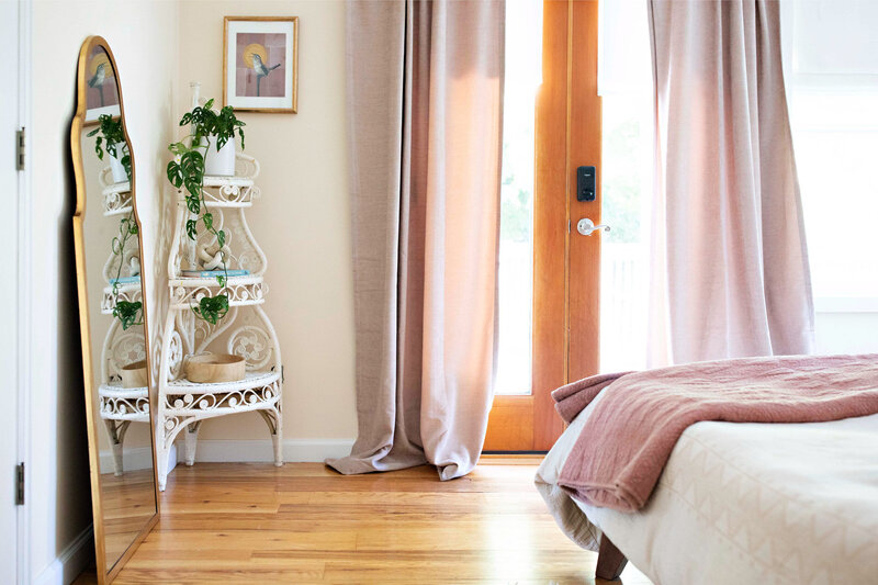 A cozy corner styled in an organic modern aesthetic, featuring a tall gold-framed mirror, a white vintage shelf and a houseplant.