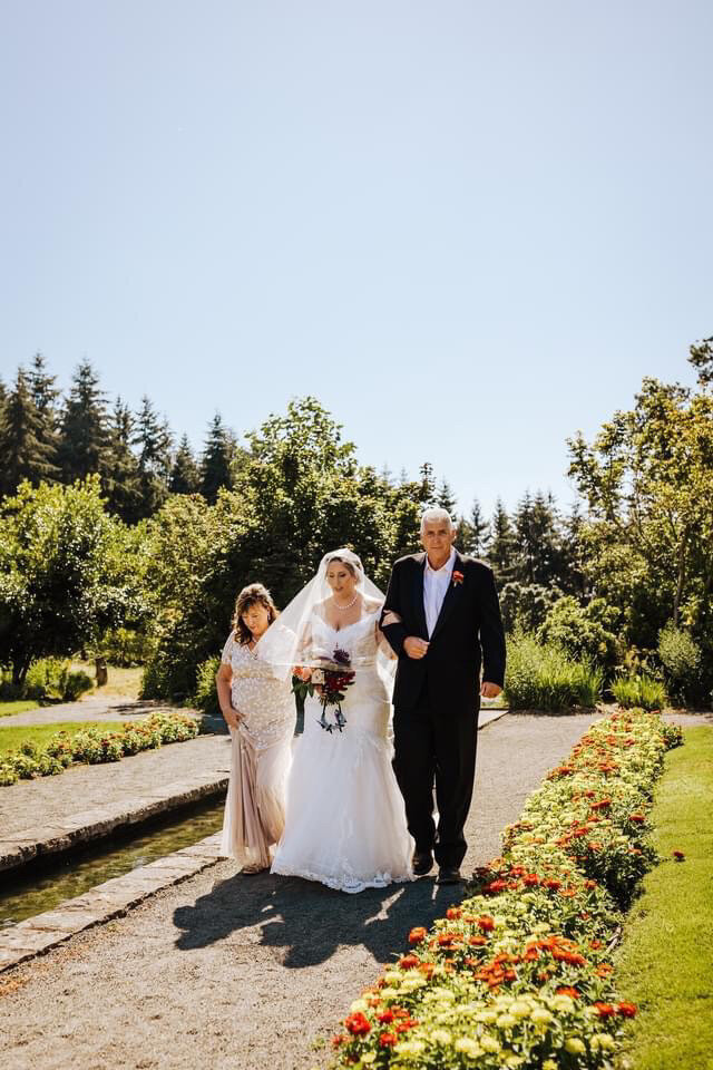 bride walking down the aisle with her parents and wearing a custom pearl bridal veil