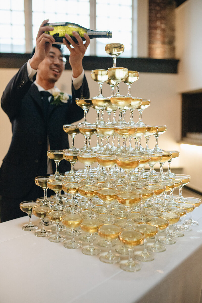Person filling the wine glass to the wine tower
