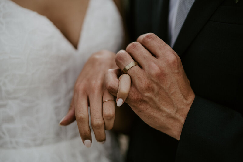 Close-up of couple holding hands and showing off wedding rings after their Breckenridge mountain ceremony.