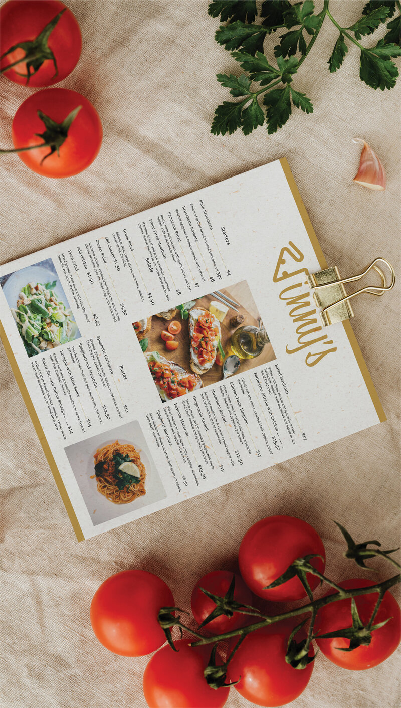 Eat in menu for Vinnys created by Ayanna Richilano Designs sitting on a table with fresh tomoatos and herbs scattered around
