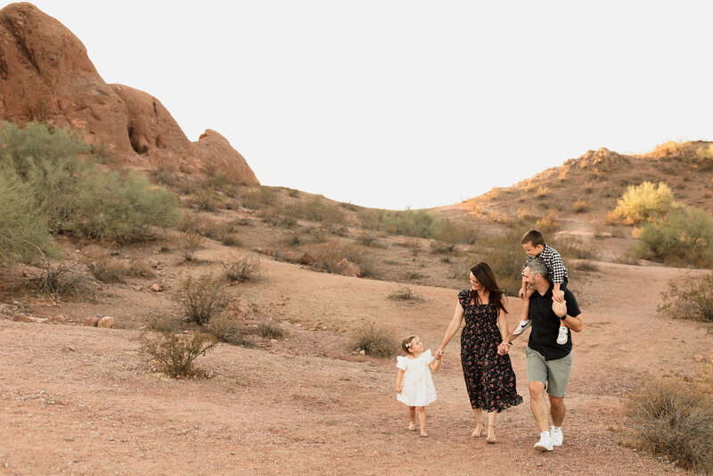 family of four walking towards the camera at papago park in arizona