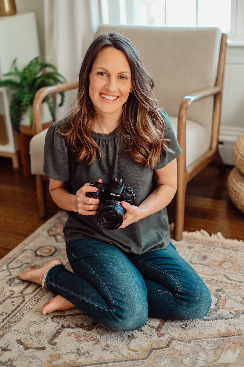 Woman wearing jeans sitting on the floor holding the camera