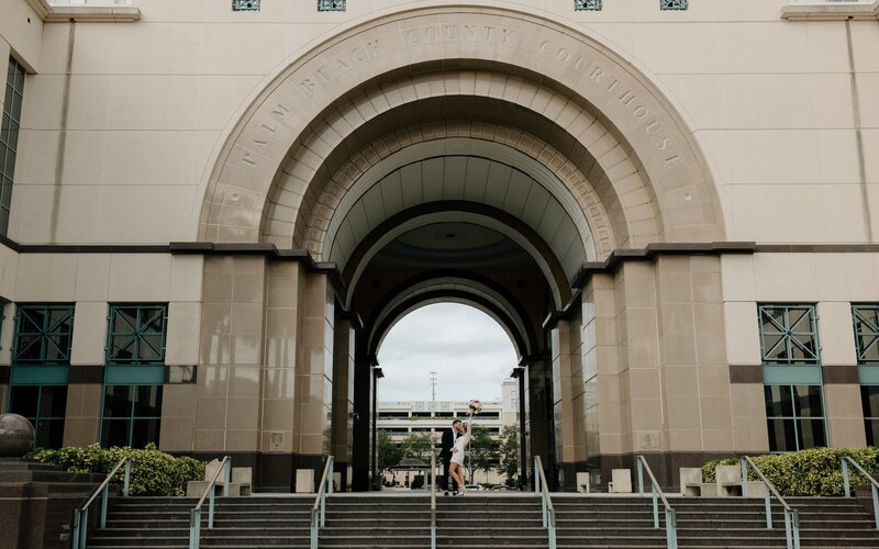 newly wed couple kiss in front of courthouse