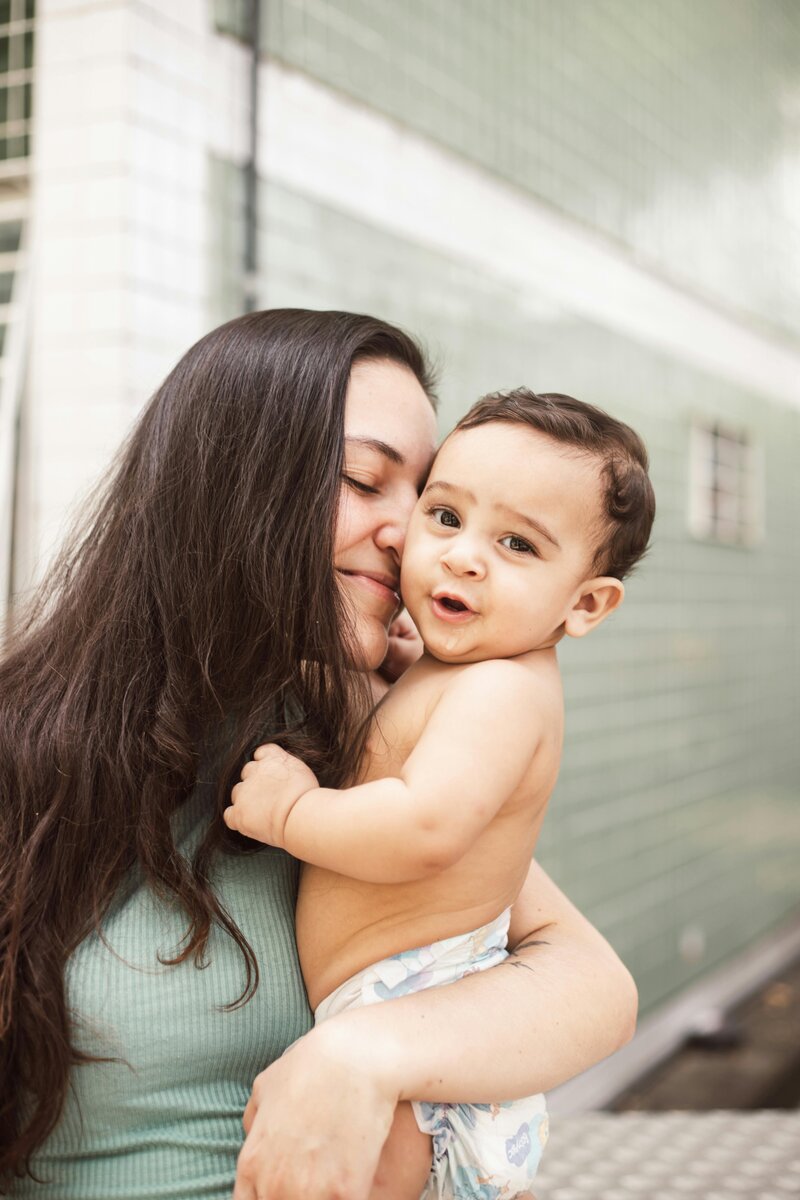 A woman lovingly kisses her baby while holding them close, showcasing a tender moment of affection.