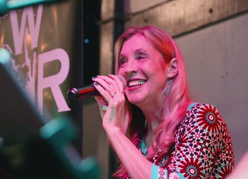 A person smiling and singing on stage 