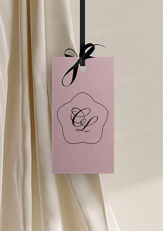 Maquette de présentation de l'identité visuelle de Cajole Lingerie, qui représente la délicatesse féminine de la lingerie. L'image montre une étiquette de la marque avec pour symbole le logo icône aux couleurs du branding.