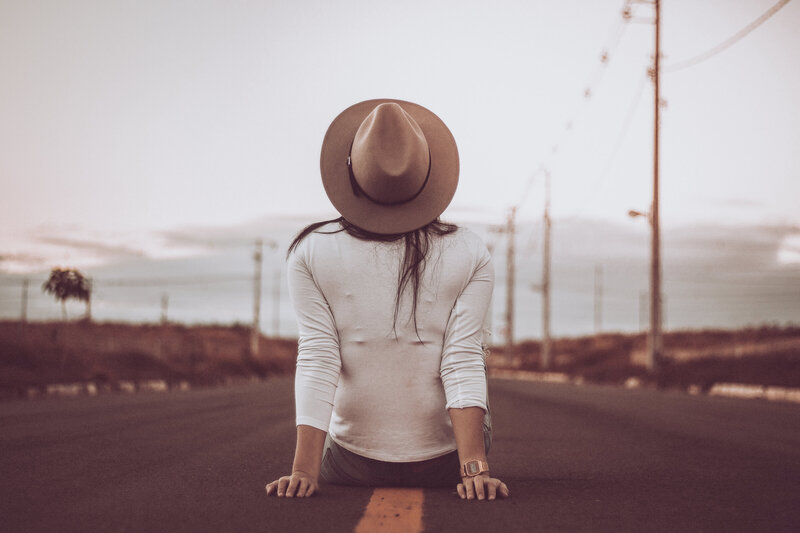 Woman in a brown hat sitting on the road