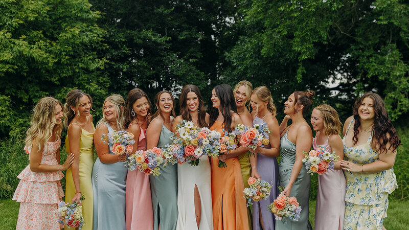 Bridesmaids laughing together in different pastel color dresses